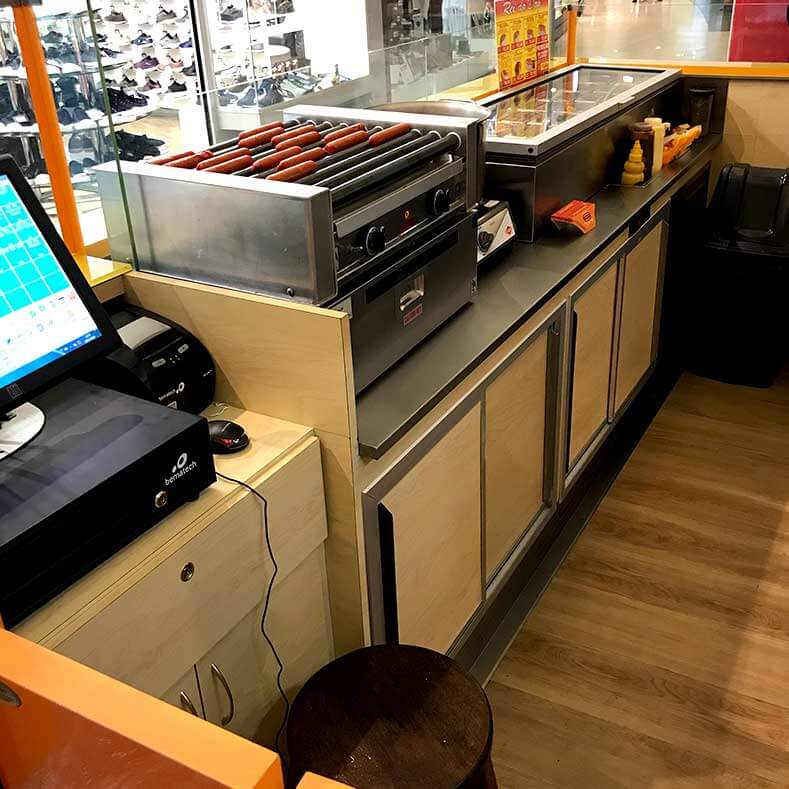 FreeArt - Vista interna do quiosque com caixa e balcão de montagem de sanduíches.